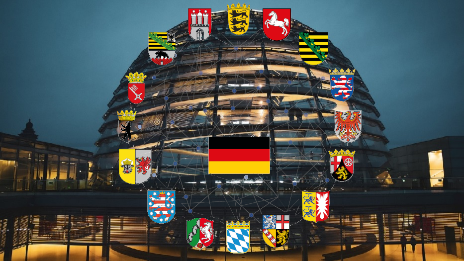 16 Logos der Bundesländer, sowie die Fahne der Bundesrepublik Deutschland vor dem Reichtagsgebäude.